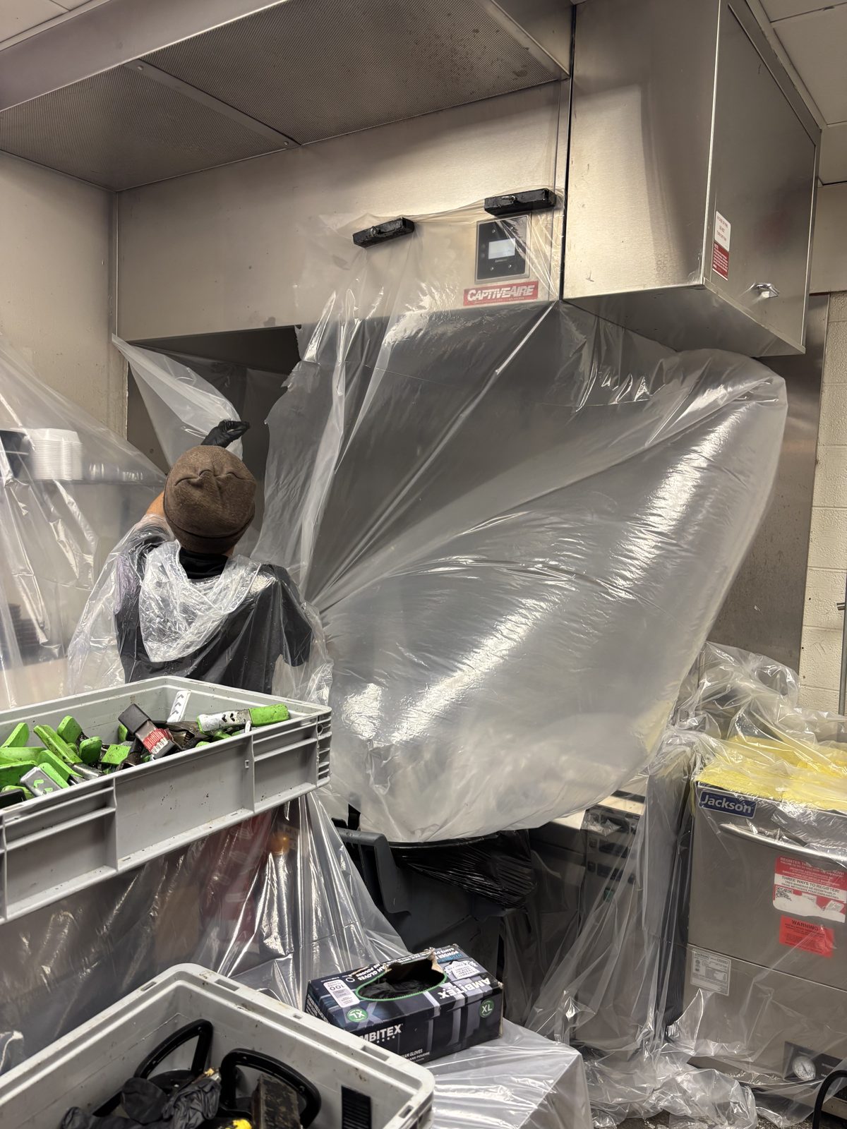 Kitchen Guard of El Paso technician wrapping a commercial kitchen hood in plastic before cleaning
