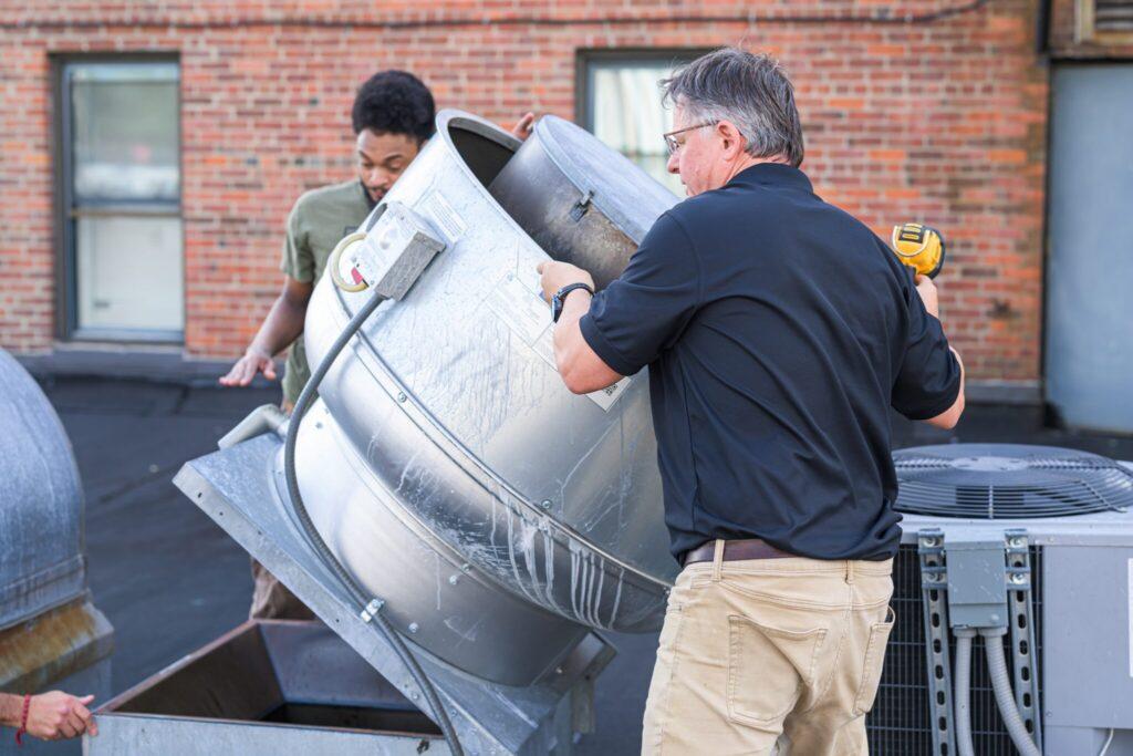 Kitchen Guard technicians tilting a rooftop exhaust fan open for cleaning