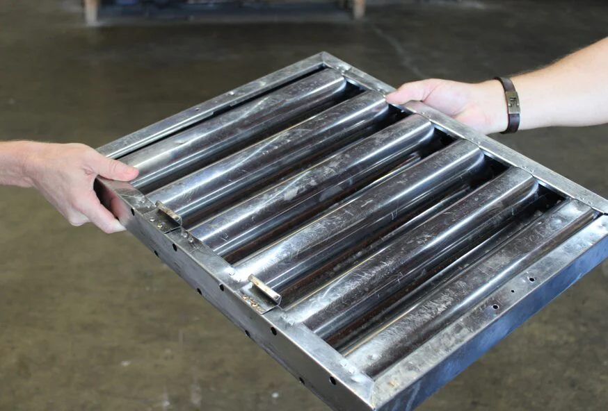Technician holding a stainless steel commercial hood baffle filter