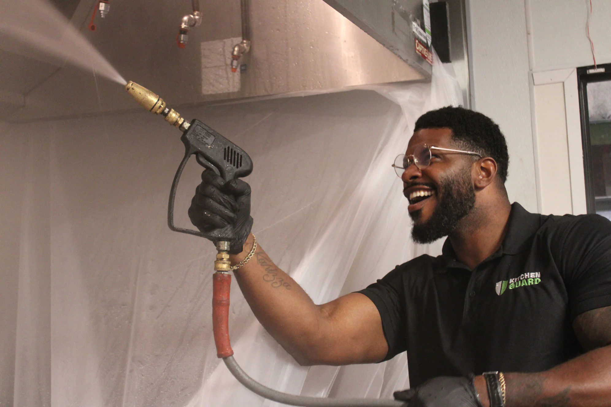 Kitchen Guard technician pressure-washing a commercial kitchen exhaust hood during a scheduled cleaning