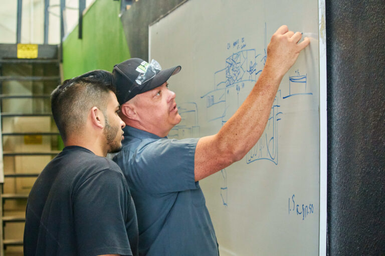 two men writing on whiteboard planning