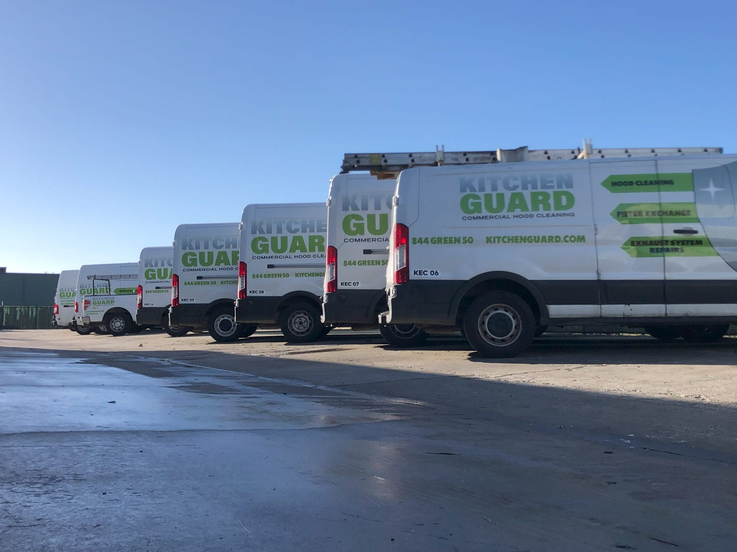 image of 8 vans of Kitchen Guard lined up in a parking lot