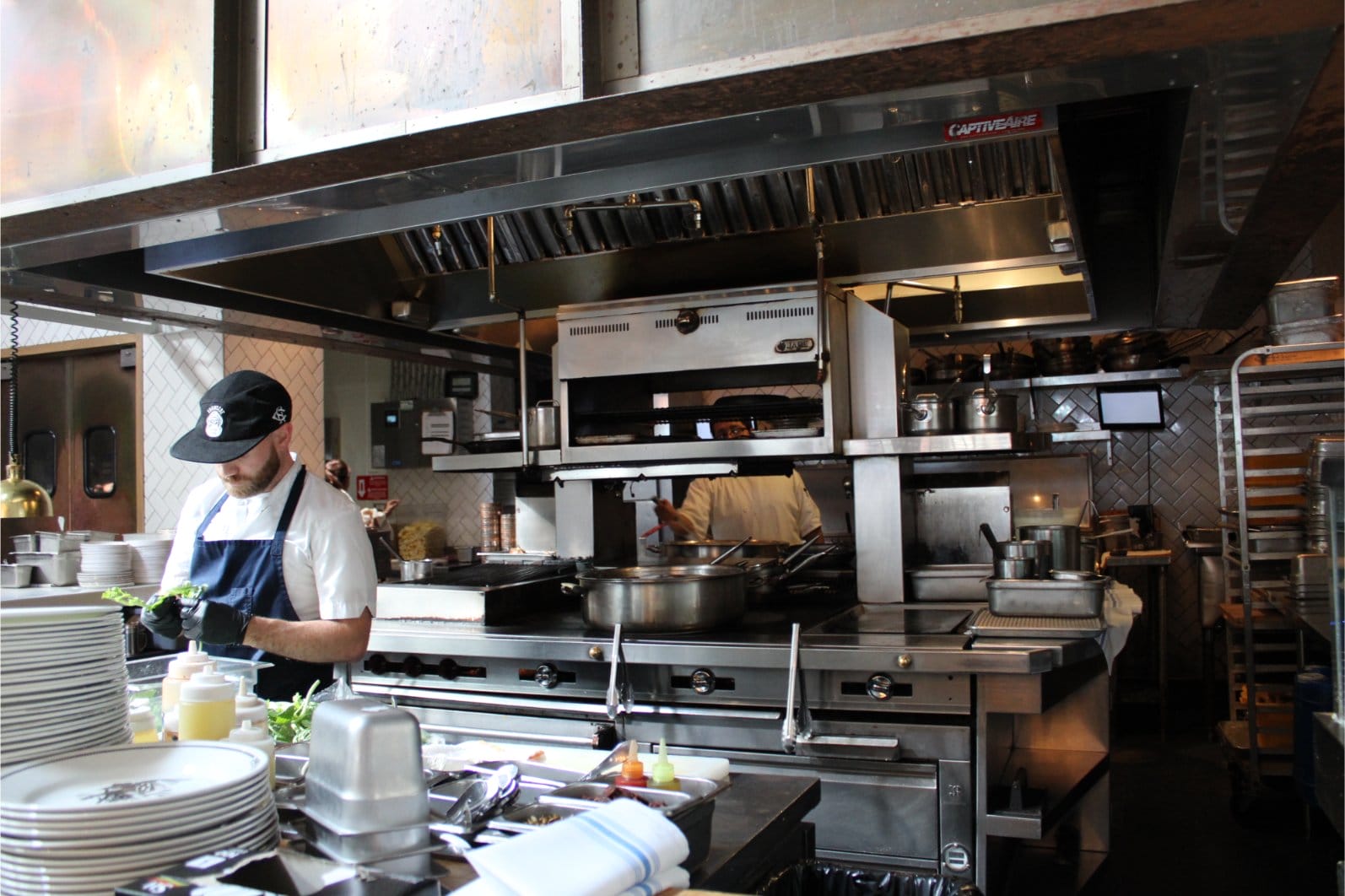 image of a kitchen showing the stainless steel vent system with a chef on the left